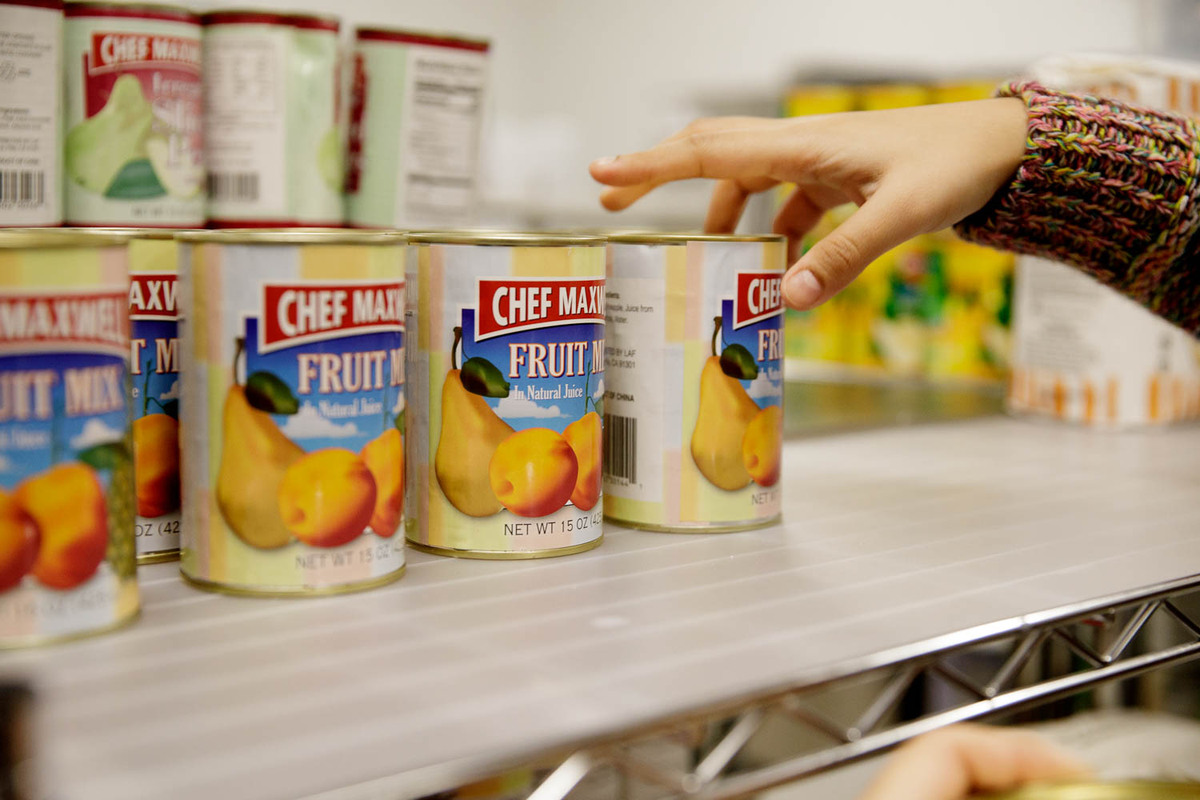 The Store volunteers restock the pantry's shelves with canned fruits and vegetables.