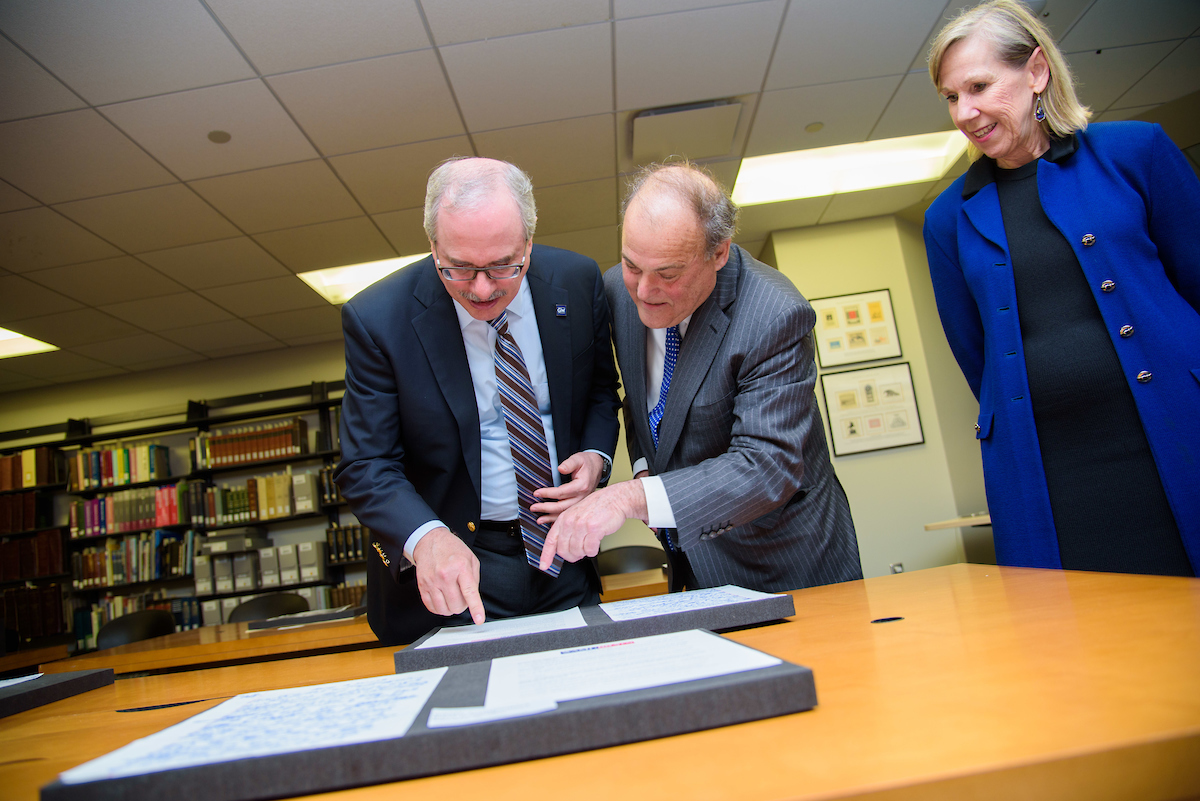 GW President Thomas LeBlanc, Mark Plotkin, and Geneva Henry, dean of GW Libraries and Academic Innovation examine the collection