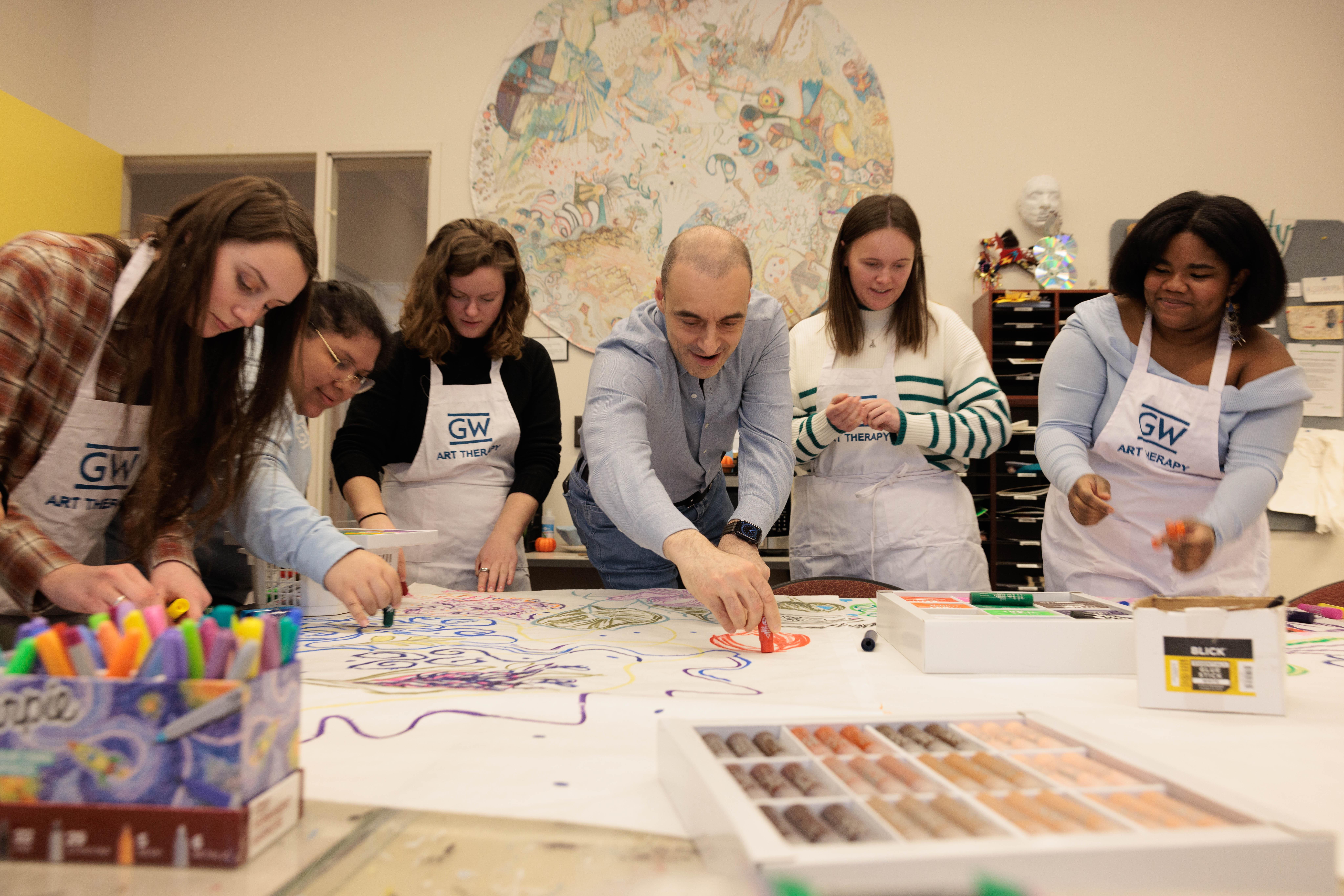 Ulvi Kasimov with Art Therapy students at an art table.