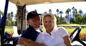 Saul and Joyce Brandman in a golf cart on a golf course on a sunny day. (Photo courtesy of Michelle Rubin)